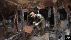 A sapper inspects a damaged Russian self-propelled artillery vehicle installed as a symbol of war in central Kyiv, Ukraine, June 15, 2023. 