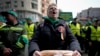 FILE - A woman holds a loaf of bread during a farmers' protest in front of the Representative Office of the European Commission in Bucharest, Romania, on, April 7, 2023.