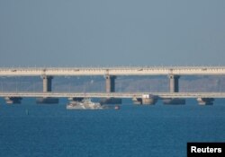 An armed ship sails next to Crimean bridge connecting the Russian mainland with the peninsula across the Kerch Strait, Crimea, July 17, 2023.