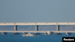 An armed ship sails next to Crimean bridge connecting the Russian mainland with the peninsula across the Kerch Strait, Crimea, July 17, 2023.
