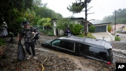 Residents evacuate past damaged vehicles after storms caused a mudslide in the Beverly Crest area of the city of Los Angeles in the U.S. state of California, Feb. 5, 2024.