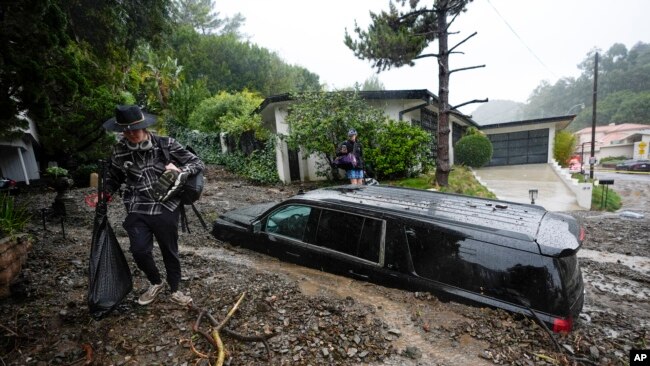 Residents evacuate past damaged vehicles after storms caused a mudslide in the Beverly Crest area of the city of Los Angeles in the U.S. state of California, Feb. 5, 2024.