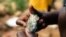 FILE - A Zimbabwean miner holding an ore sample that they found while searching for gold in Kadoma, February 15, 2019.
