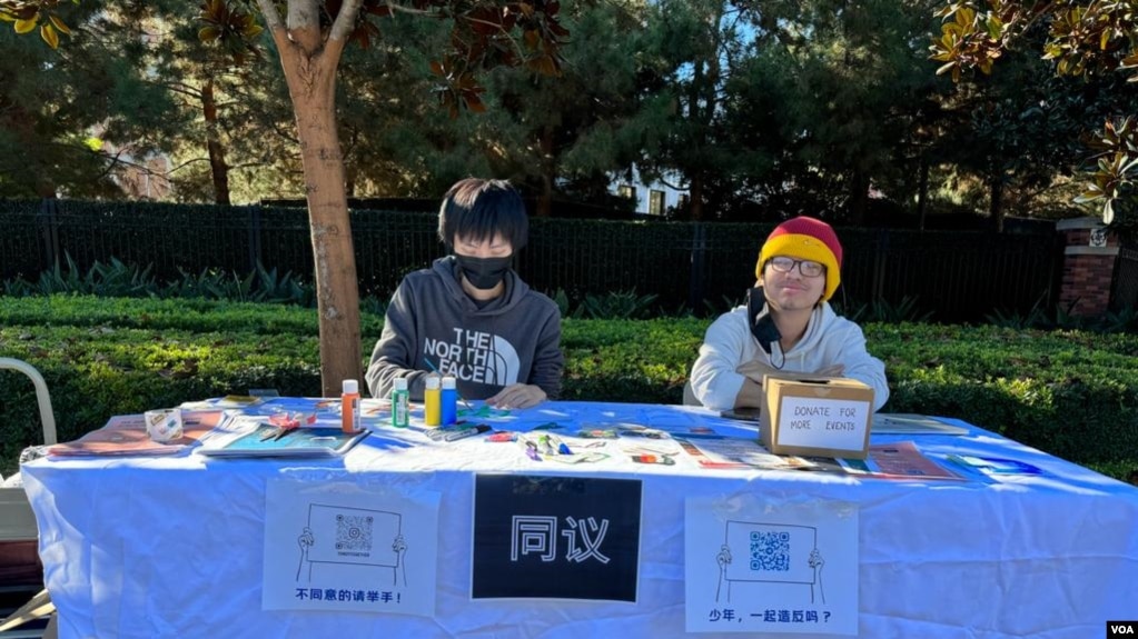 纪念白纸运动一周年的中国留学生和异议人士在南加州大学主校区大门口设有展位，桌上摆放着有关白纸运动的传单、签字笔、固体胶、艺术画布、明信片、“抗争贴画”等。 （美国之音 张木林）