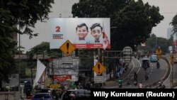 Masyarakat berjalan melewati baliho Menteri Pertahanan dan calon Presiden Prabowo Subianto dan pasangannya Gibran Rakabuming Raka di Jakarta, 12 Januari 2024. (Foto: REUTERS/Willy Kurniawan)