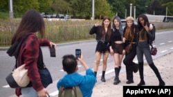 In this undated photo provided by AppleTV+, K-pop band Blackswan members have their photos taken. (AppleTV+ via AP)