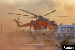 Vatrogasni helikopter uzima vodu iz bazena, dok požari gore oko sela Genadi, na ostrvu Rodos, Grčka, 25. jula 2023.