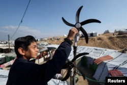 Displaced Palestinian teenager Hussam Al-Attar works on wind turbines, that he uses to light up his shelter during power cut, at a tent camp in Rafah, in the southern Gaza Strip, February 6, 2024. (REUTERS/Ibraheem Abu Mustafa)