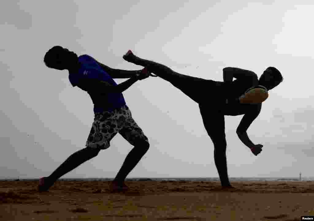 Dua pria melakukan latihan seni bela diri di pantai di kota pinggiran Kolombo, Sri Lanka.