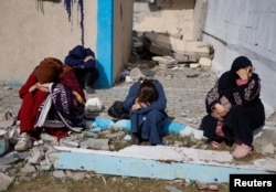 People rest next to damaged buildings as Palestinians arrive in Rafah, having been evacuated from Nasser Hospital in Khan Younis because of the Israeli ground offensive against Hamas, in the southern Gaza Strip, Feb. 15, 2024.