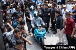 Calon wakil presiden Gibran Rakabuming Raka (tengah) tiba di lokasi kampanye akbar Stadion Gelora Bung Karno bersama istrinya dengan mengendarai motor listrik, Jakarta, Sabtu, 10 Februari 2024. (Foto: Yasuyoshi Chiba/AFP)