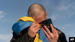 Upravo razmenjeni ukrajinski ratni zarobljenik plače dok telefonom razgovara sa članovima svoje porodice, nakon razmene zarobljenika na granici Ukrajine i Rusije, 31. januara 2024.