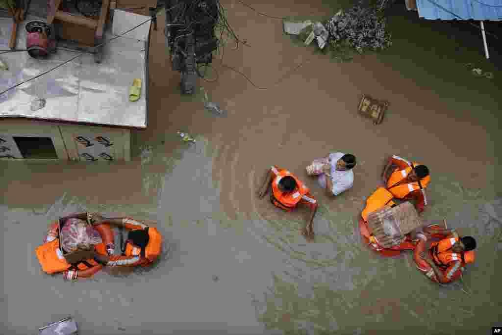 National Disaster Response Force (NDRF) personnel distribute relief material to flood-affected people stuck in a low-lying area around the river Yamuna in New Delhi, India.