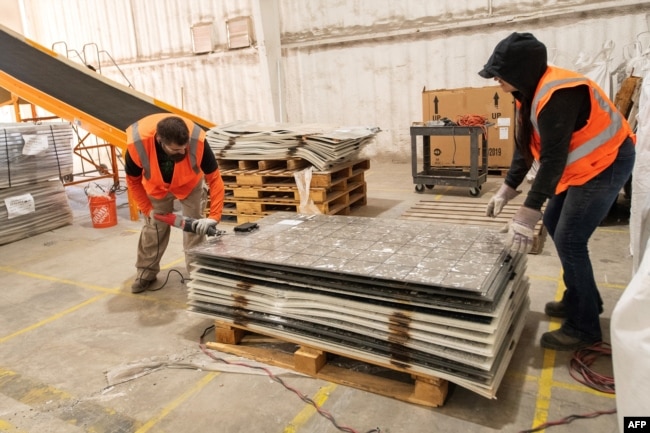 Workers dismantle solar panels to be recycled at the We Recycle Solar plant in Yuma, Arizona, Dec. 6, 2023. (Photo by VALERIE MACON / AFP)