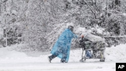 A pedestrian pushes a shopping cart during a heavy snowfall, Nov. 9, 2023, in Anchorage, Alaska.