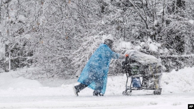 A pedestrian pushes a shopping cart during a heavy snowfall, Nov. 9, 2023, in Anchorage, Alaska.