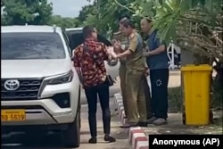 In this image made from a video by a source wishing to remain anonymous, one of the two activists, left, travelng with Chinese rights lawyer Lu Siwei, right, argues with police detaining Lu, July 28, 2023. (Anonymous Source via AP)