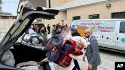 FILE - Officials transport new blankets into St. Anthony Croatian Catholic Church, hosting newly arrived migrants in the Chinatown area of Los Angeles, June 14, 2023.