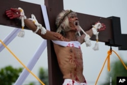 Wilfredo Salvador grimaces after he was nailed to the cross during a reenactment of Jesus Christ's sufferings as part of Good Friday rituals in the village of San Pedro, Cutud, Pampanga province, northern Philippines, April 7, 2023.