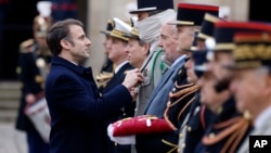 FILE - French President Emmanuel Macron awards a member of the special forces during a military ceremony in the courtyard of the Hotel National des Invalides in Paris, Feb. 19, 2024.