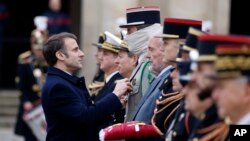 资料照片：2024年2月19日，法国总统马克龙在巴黎国家荣军院举行的军事仪式上为一名特种部队成员授勋。（美联社照片）