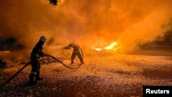 ইউক্রেনের ওডেসা অঞ্চলের দানিউব নদীর তীরে একটি বন্দরে রাশিয়ার ড্রোন হামলার সময় দমকলকর্মীরা ক্ষতিগ্রস্ত ট্রাকগুলোর আগুন নেভাচ্ছে। ২৬ সেপ্টেম্বর, ২০২৩। (রয়টার্সের মাধ্যমে ইউক্রেনের রাষ্ট্রীয় জরুরি পরিষেবা)