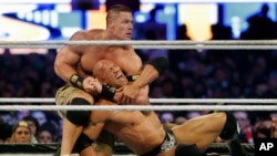 FILE - Wrestler John Cena, top, chokes Dwayne "The Rock" Johnson at a Wrestlemania event, April 7, 2013, in East Rutherford, N.J.