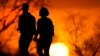 FILE - Sepasang suami istri berjalan melalui taman saat matahari terbenam, 10 Maret 2021, di Kansas City, Mo. (AP/Charlie Riedel)