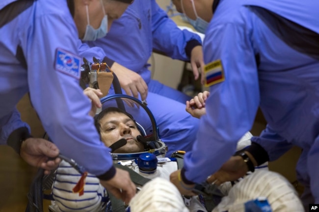 FILE - Russian Space Agency experts test a space suit of Russian cosmonaut Oleg Kononenko, ahead of a launch at the Russian leased Baikonur Cosmodrome, in Kazakhstan, Wednesday, July 22, 2015. (AP Photo/Pavel Golovkin, File)