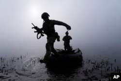 Seorang prajurit Ukraina melompat keluar dari perahu di tepi sungai Dnipro di garis depan dekat Kherson, Ukraina, Minggu 15 Oktober 2023. (AP Photo/Mstyslav Chernov)