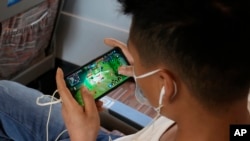 FILE - A man plays an online game from Chinese gaming platform Tencent on a train from Henan to Beijing, Sept. 15, 2021.