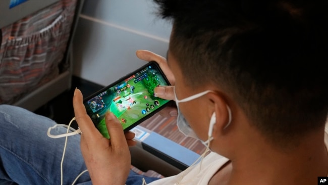 FILE - A man plays an online game from Chinese gaming platform Tencent on a train from Henan to Beijing, Sept. 15, 2021.