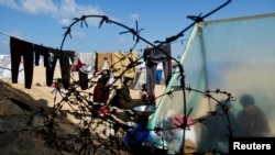 Displaced members of Palestinian Abu Mustafa family, who fled their house due to Israeli strikes, shelter at the border with Egypt, in Rafah in the southern Gaza Strip, Feb. 10, 2024. 