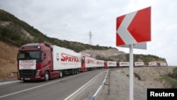 Trucks transporting humanitarian aid for residents of Nagorno-Karabakh head toward the Armenia-Azerbaijan border on a road near the village of Kornidzor, Armenia, Sept. 23, 2023.