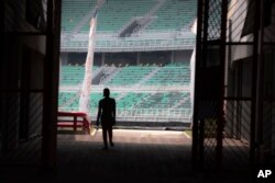 Siluet seorang pekerja menghadap kursi penonton di Stadion Gelora Bung Tomo, Surabaya, Jawa Timur, salah satu venue yang dipersiapkan menjadi tuan rumah FIFA U-20 World Cup, Kamis, 30 Maret 2023. (AP/Trisnadi)