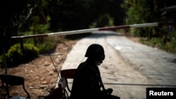 FILE - A Thai soldier sits in front of the blockage of a road near the Thailand-Myanmar border, in Mae Sot district, Tak province, Thailand, Dec. 19, 2021. 