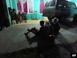 Orang-orang menunggu di luar rumah mereka setelah gempa bumi menggoncang kabupaten Bantul, di luar Yogyakarta, Jumat, 30 Juni 2023. (AP/Mahmud)