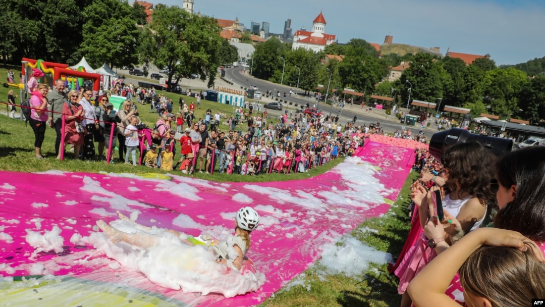 A participant slips down a water slide during the Saltibarsciai Slip and Slide competition during the Pink Soup Fest in Vilnius, June 10, 2023.