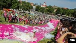 A participant slips down a water slide during the Saltibarsciai Slip and Slide competition during the Pink Soup Fest in Vilnius, June 10, 2023.