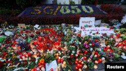 FILE - Flowers and candles are seen at a makeshift memorial near a sign marking the 650th anniversary of the city of Solingen, following a stabbing rampage there, in Solingen, Germany, Aug. 26, 2024.