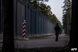 FILE - A border guard patrol along the border wall at Polish - Belarus border not far from Bialowieza, eastern Poland, May 29, 2023.