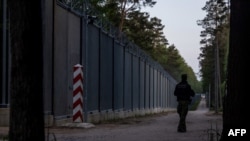 FILE - A border guard patrol along the border wall at Polish - Belarus border not far from Bialowieza, eastern Poland, May 29, 2023. 