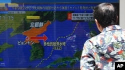 A man stands along a sidewalk to watch a TV showing a news program on North Korea's missile launch, July 12, 2023, in Tokyo.