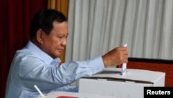 Capres Prabowo Subianto memasukan surat suara ke dalam kotak suara ketika menggunakan hak pilihnya di TPS Bojong Koneng, di Bogor, Jawa Barat, pada 14 Februari 2024. (Foto: Reuters/Kim Kyung-Hoon)