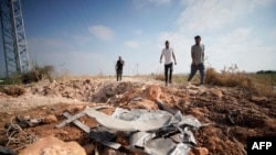 Palestinian men walk towards a crater and debris caused by an improvised explosive device which targeted an Israeli military jeep, in the northern Palestinian city of Jenin, in the Israeli occupied West Bank on June 27, 2024.
