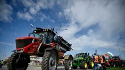 Sejumlah petani mengendarai traktornya untuk memblokir jalan masuk truk di jembatan Danube di perbatasan Rumania dan Bulgaria, di Rousse, dalam aksi protes pada 29 Maret 2022. (Foto: AFP/Nikolay Doychinov)