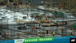 Construction workers work amid sections of rebar at a construction site in the central business district in Beijing, China, June 13, 2023. 