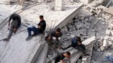 Palestinians sit by the building of the Al-Nadi family destroyed in the Israeli bombardment of the Gaza Strip in Nusseirat refugee camp, central Gaza Strip, Dec. 8, 2023. 