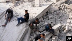 Palestinos sentados junto al edificio de la familia Al-Nadi destruido durante el bombardeo israelí de la Franja de Gaza en el campo de refugiados de Nuseirat, en el centro de la Franja de Gaza, el 8 de diciembre de 2023.