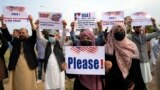 FILE - Afghan refugees protesting delays in relocation approvals by the U.S. government hold placards in Islamabad, Feb. 26, 2023.